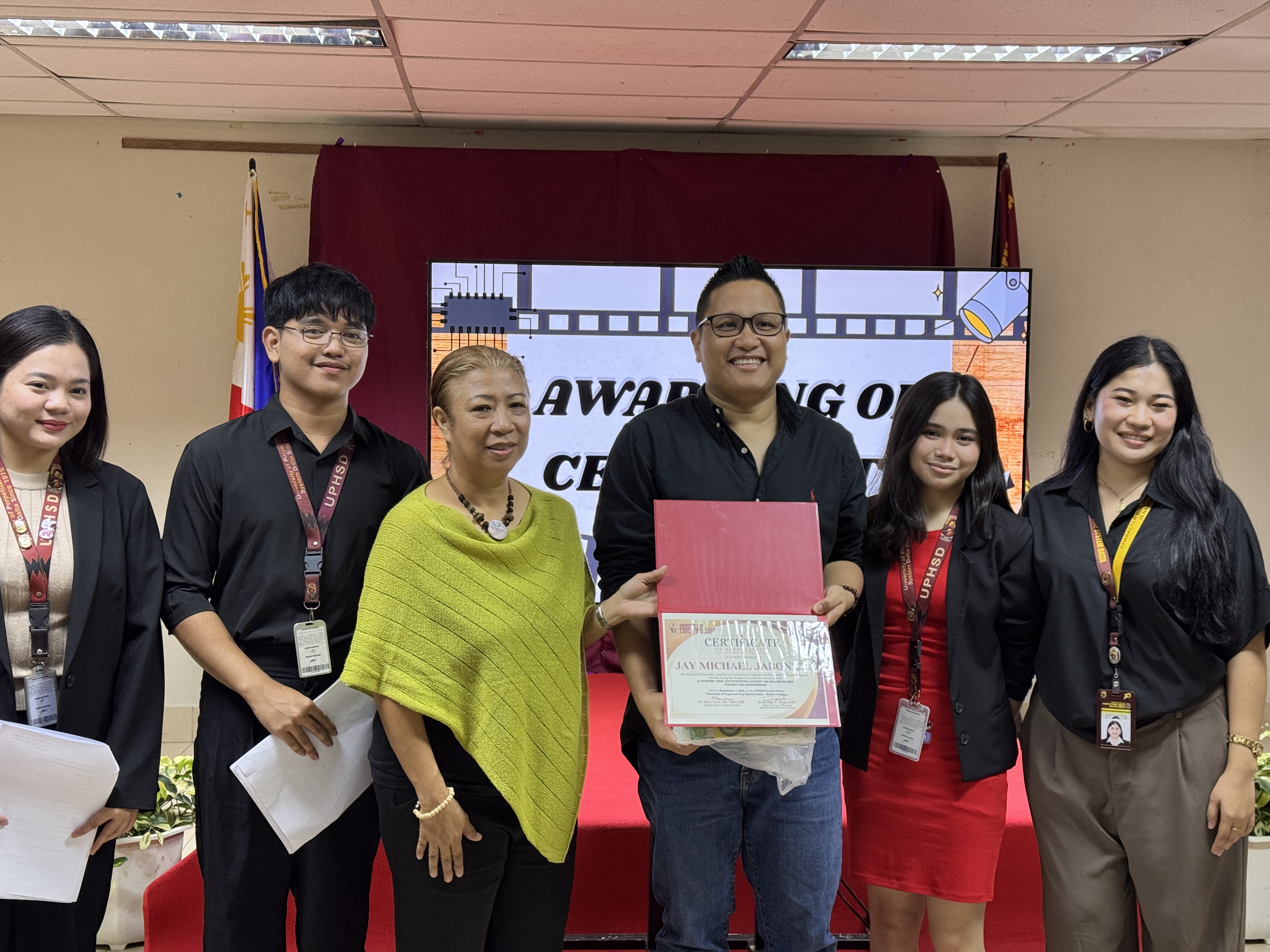 Jay Jaboneta receiving a certificate of appreciation from UPHSD Molino faculty and student representatives